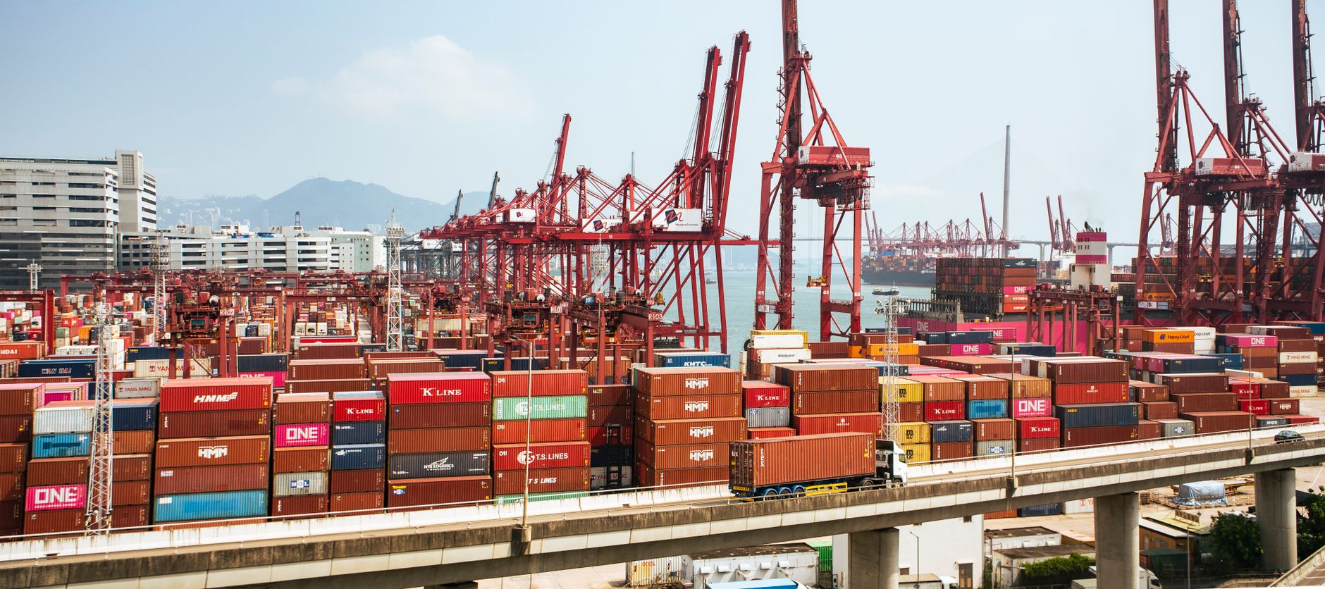 Gr&uacute;as, contenedores y camiones en una terminal portuaria de Hong Kong